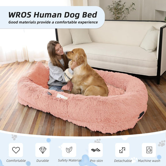 Woman sitting on a pink dog bed with a dog, in a living room setting.