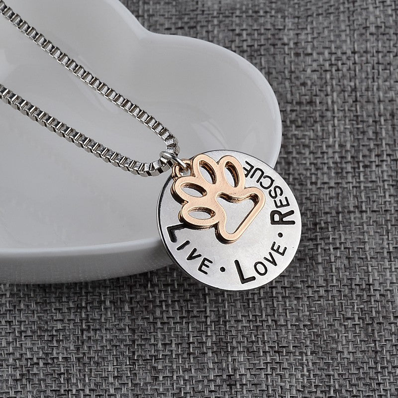 Necklace with paw print and motivational pendant on a textured surface