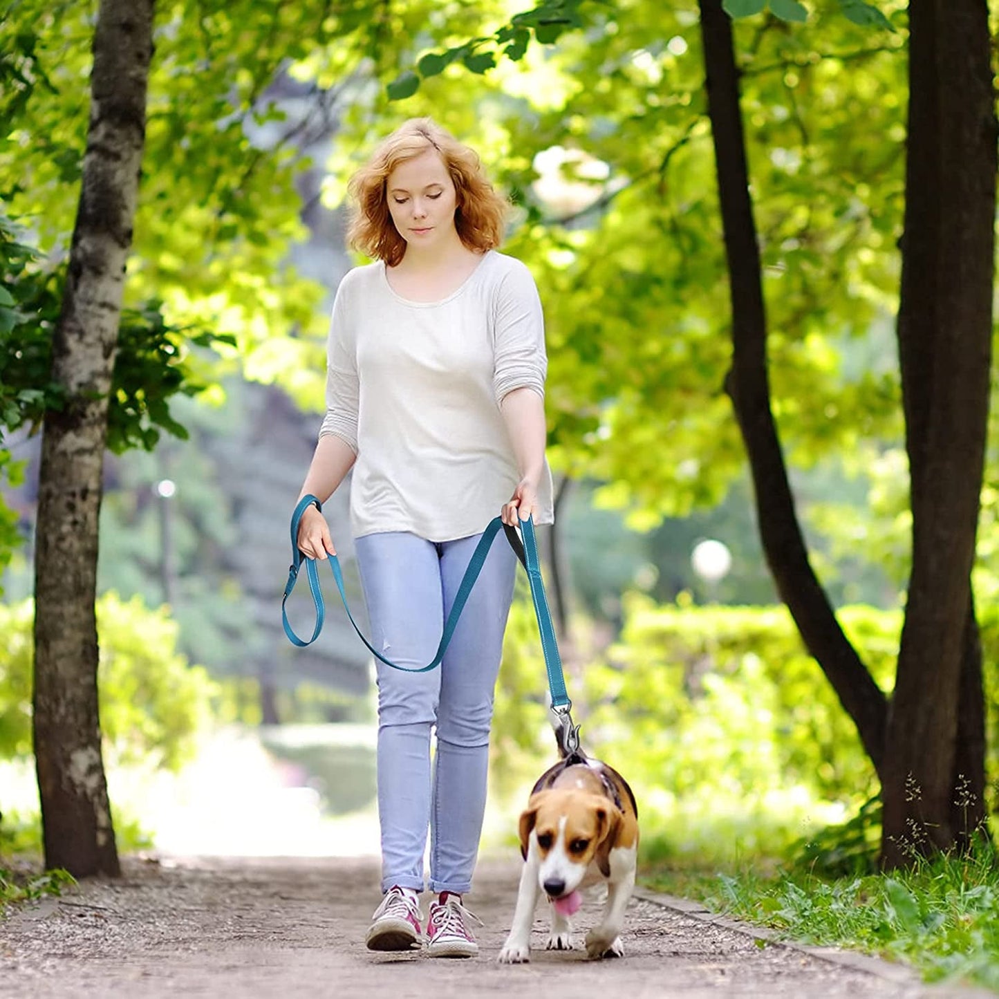 Woman walking a dog on a leash in a park