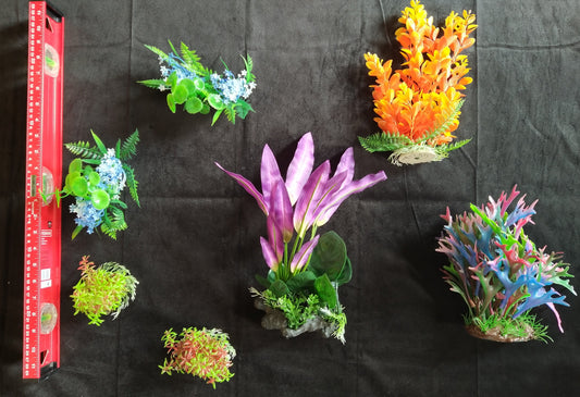 Assorted artificial aquarium plants on a black background with a ruler for scale.
