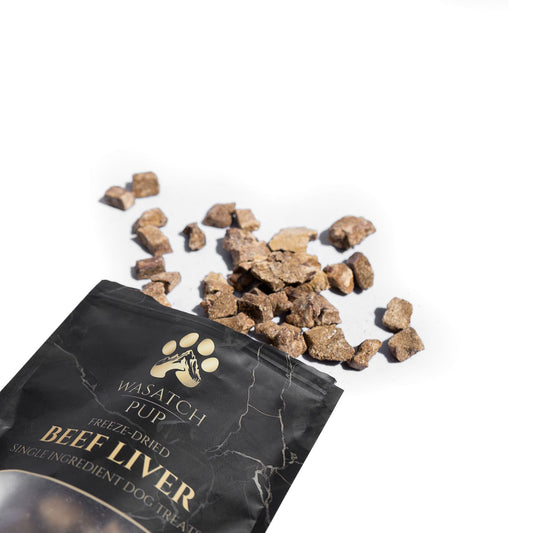 Wasatch Pup beef liver dog treats spilling out of a black packaging on a white background