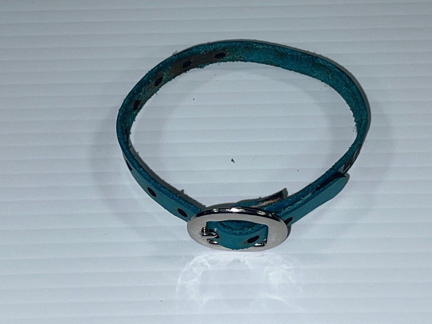 Teal leather bracelet with silver buckle on a white background