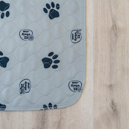 Quilted pet mat with paw prints and brand logo on a wooden floor