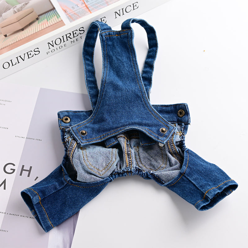 Blue denim baby romper on a white surface with a magazine underneath