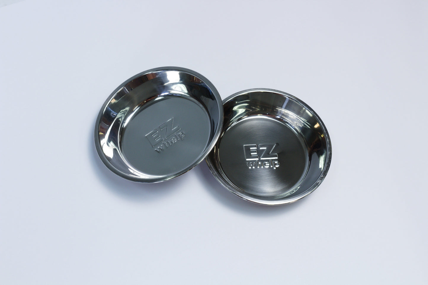Two metallic bowls with a brand logo on a light gray background