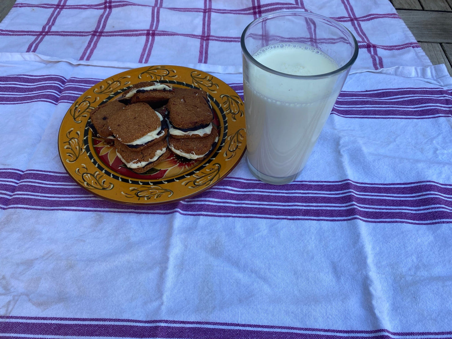 Cookies on a plate with a glass of milk on a striped tablecloth