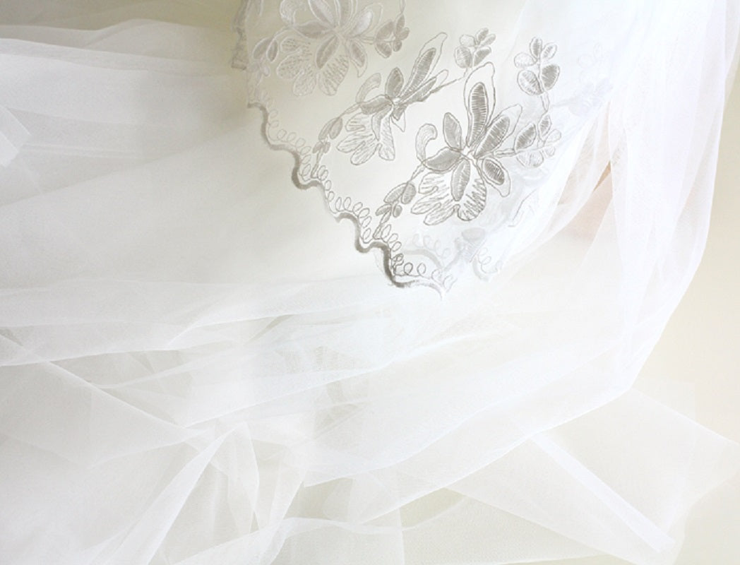 White fabric with floral lace embroidery on a light background