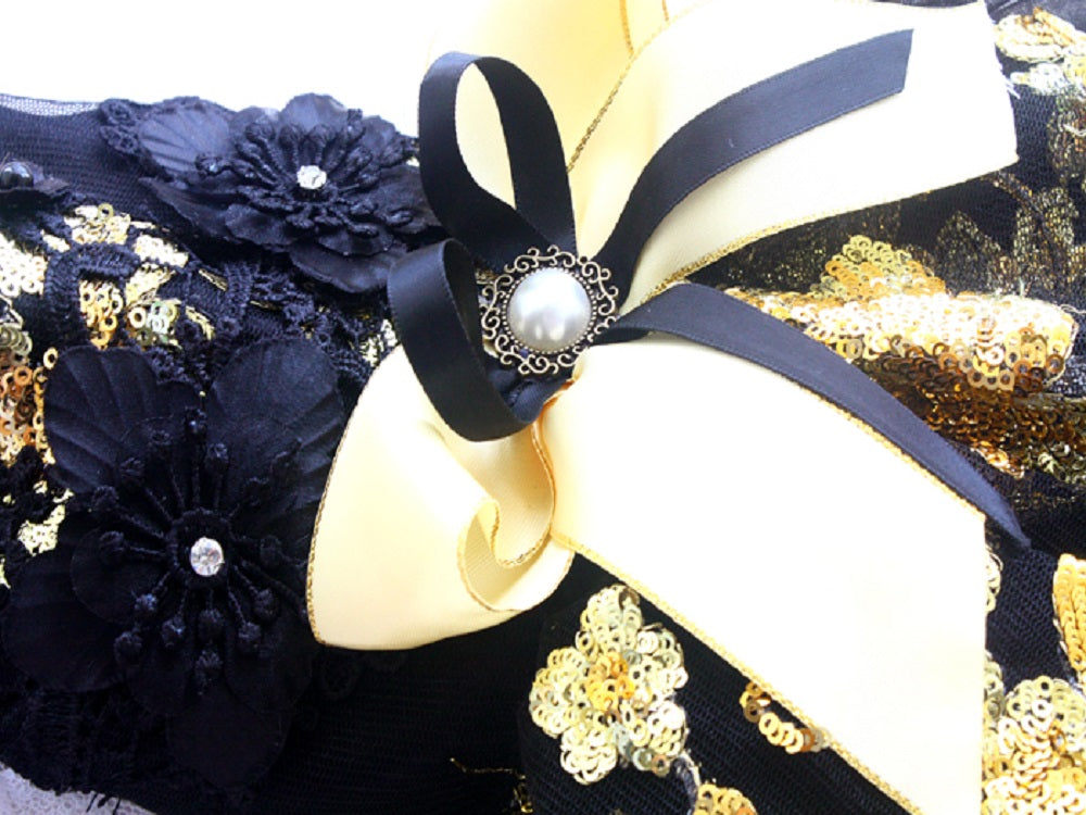 Decorative headband with black and gold flowers and ribbons on a white background