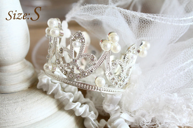 Silver tiara with pearls on a white lace background
