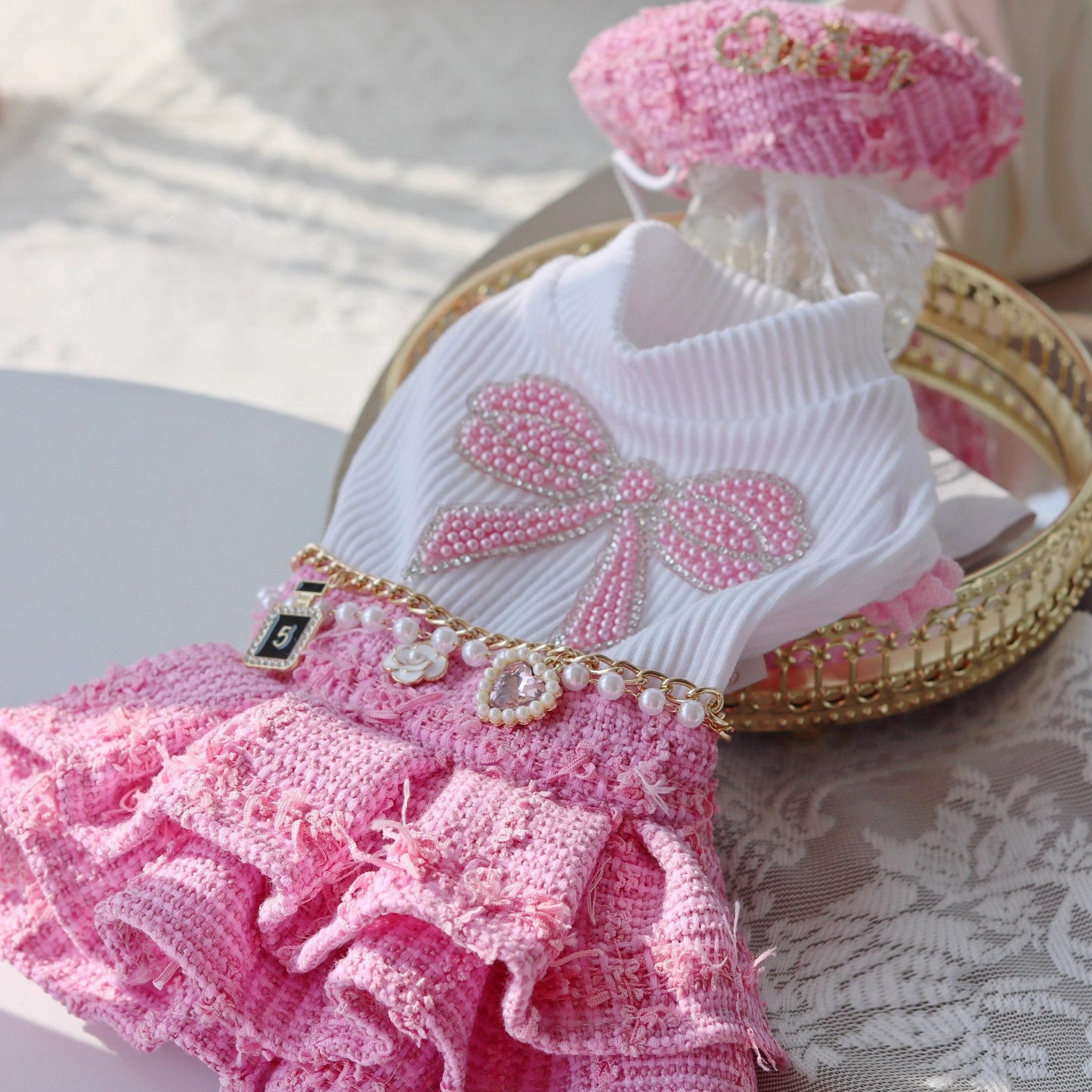 Dog outfit with pink ruffled skirt and white top on a lace surface
