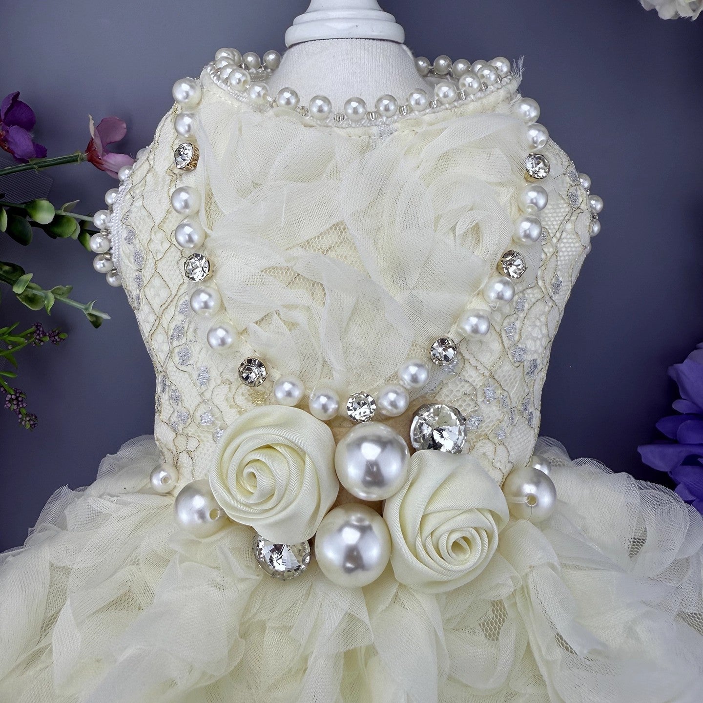 Decorative headpiece with pearls and flowers on a mannequin against a dark background