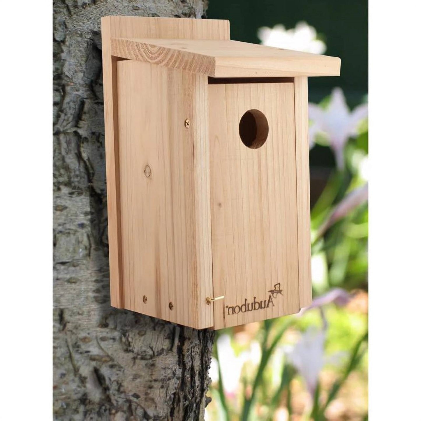 Wooden birdhouse attached to a tree trunk with a blurred natural background