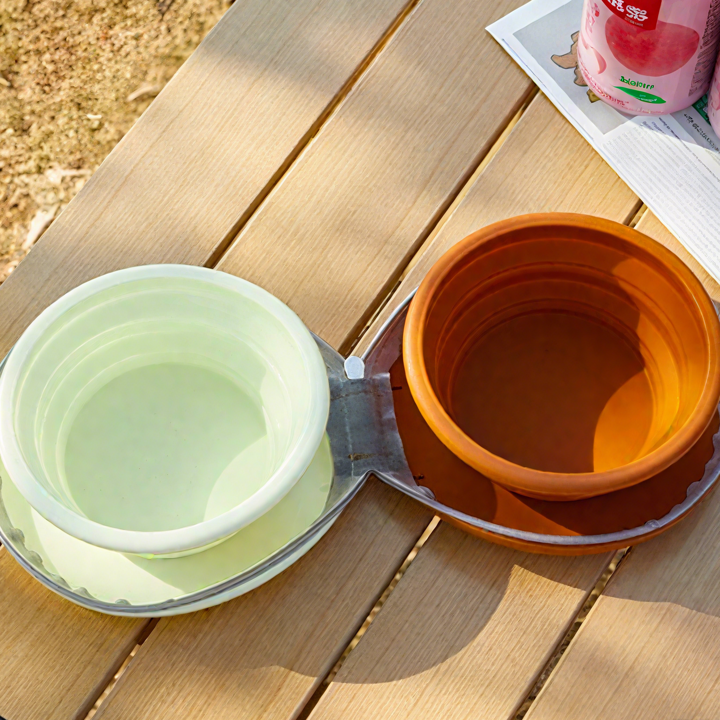 Two collapsible bowls, one green and one orange, on a wooden surface.