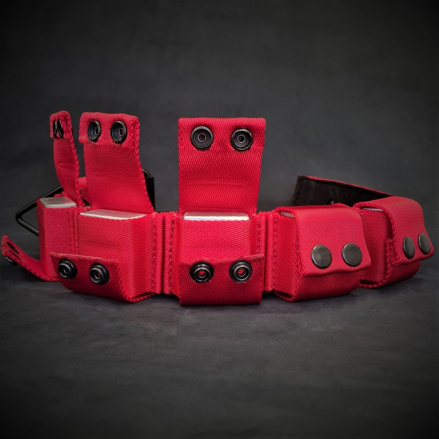 Red tactical vest with multiple pouches and straps on a dark background