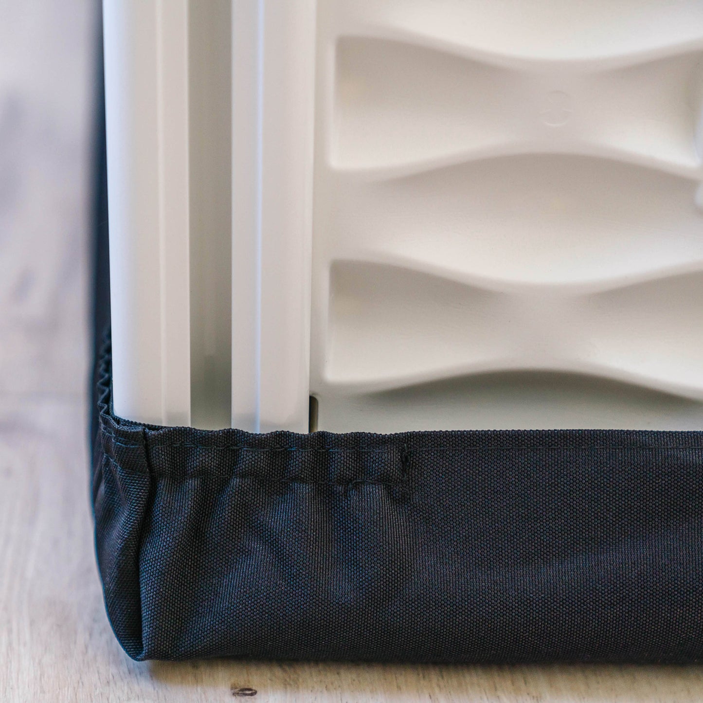 Close-up of a textured white panel with a black border on a light wooden surface.