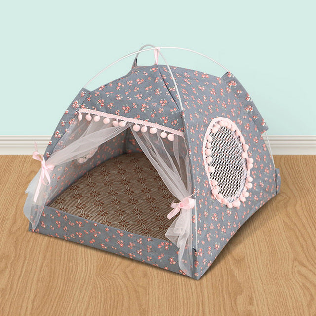 Floral-patterned pet tent with a mesh door on a wooden floor against a light blue wall.