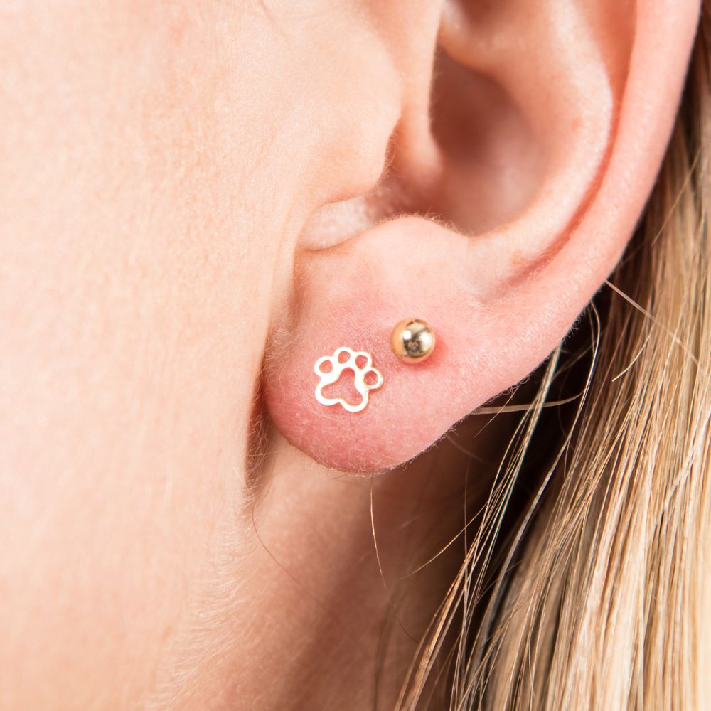 Close-up of an ear wearing a gold paw print earring.