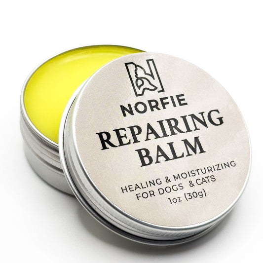 Norfie repairing balm for dogs and cats with a silver tin and yellow balm inside.