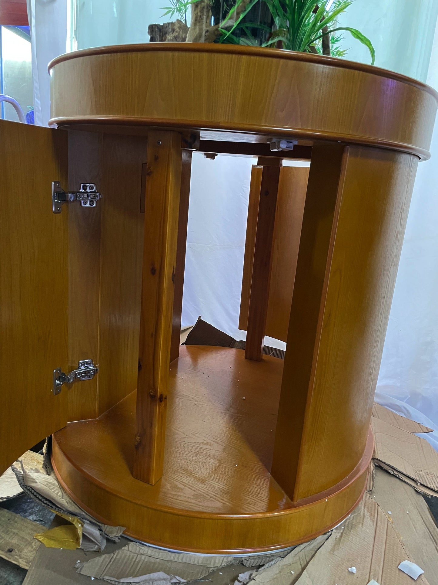 Wooden circular table with a plant on top, surrounded by cardboard boxes.