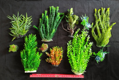 Collection of various artificial plants on a black background with a ruler for scale.