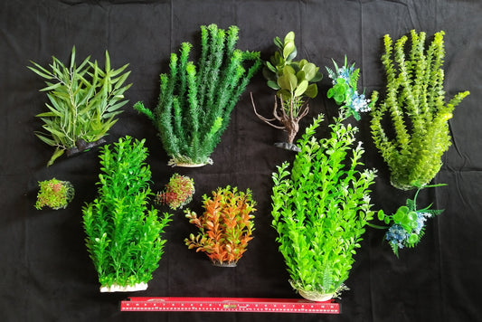 Collection of various artificial plants on a black background with a ruler for scale.