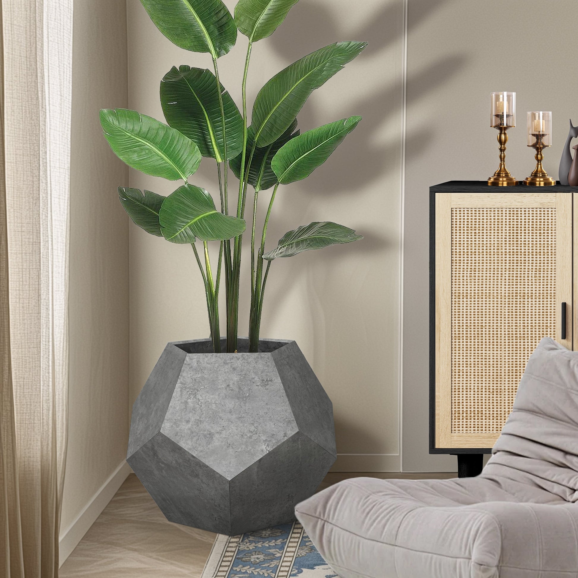 Faux plant in a geometric gray pot next to a gray sofa and decorative cabinet.