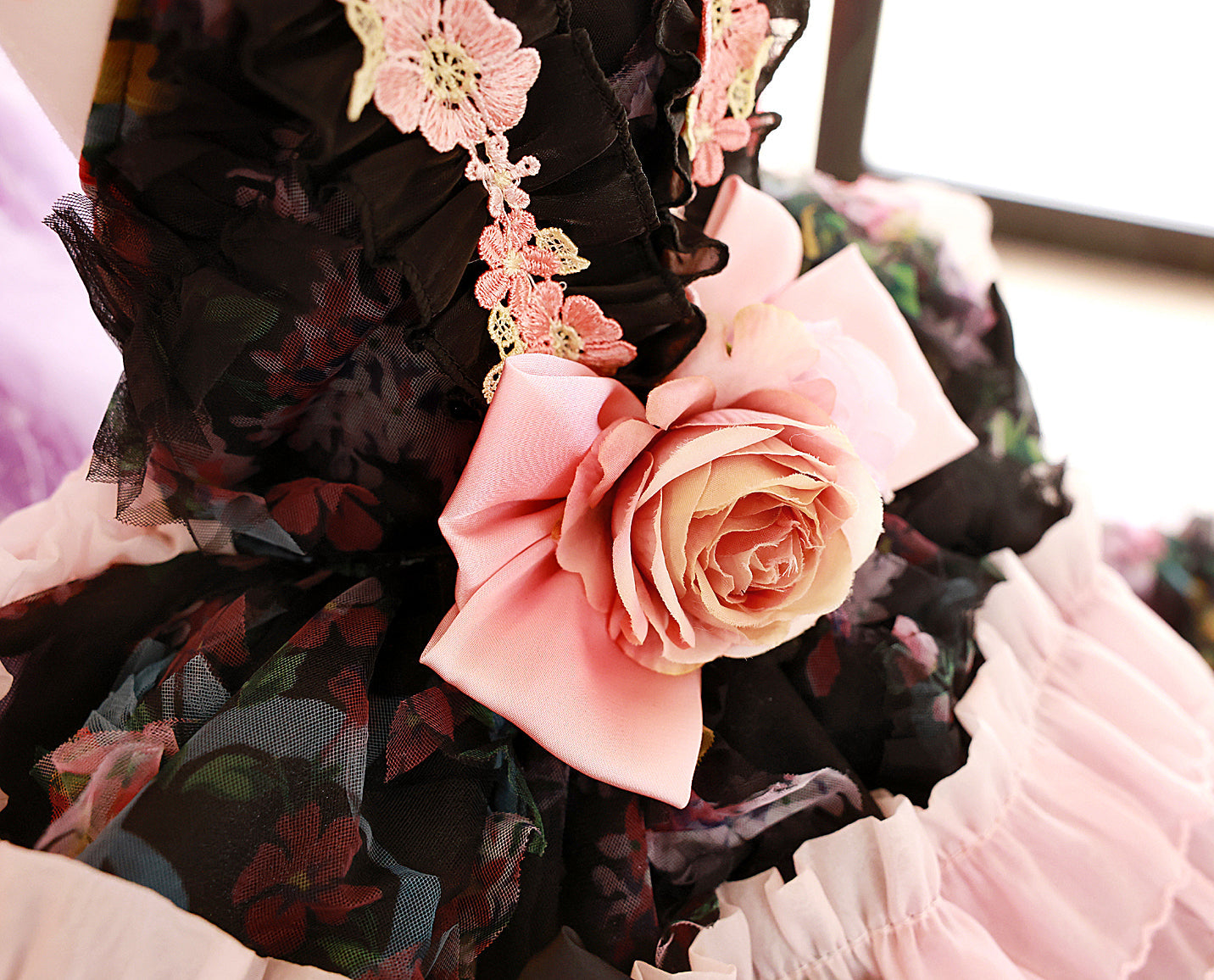 Close-up of a floral dress with pink roses and black lace details.