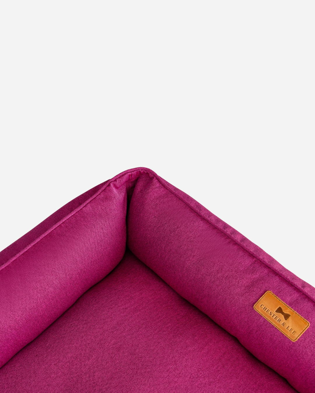 Close-up of a pink pet bed with a brand label on a white background