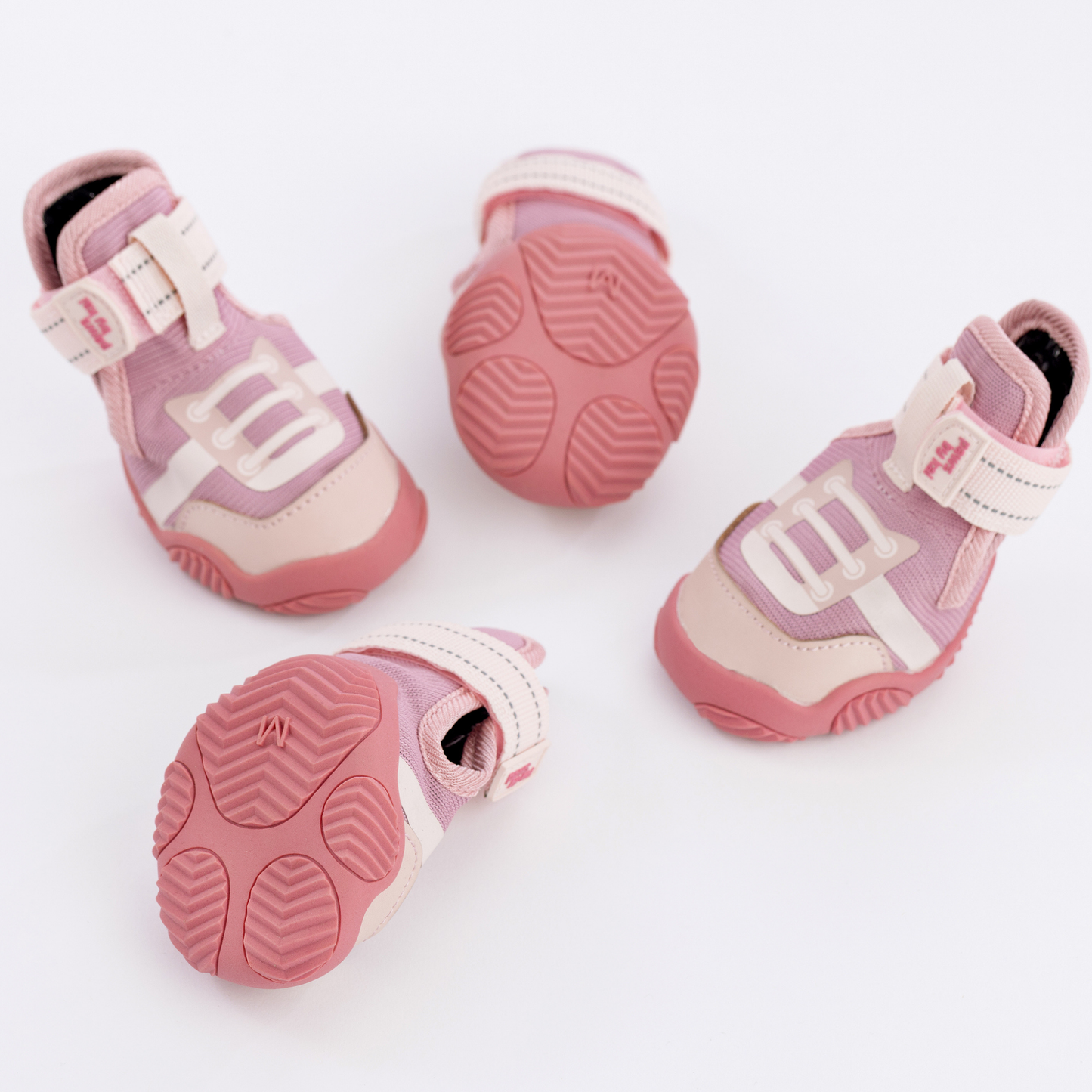 Pink and white baby shoes with textured soles on a light background