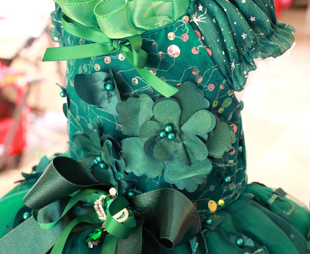 Green decorative dress with flowers and ribbons on a blurred background