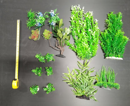 Assorted artificial green plants on a gray background with a tape measure for scale.