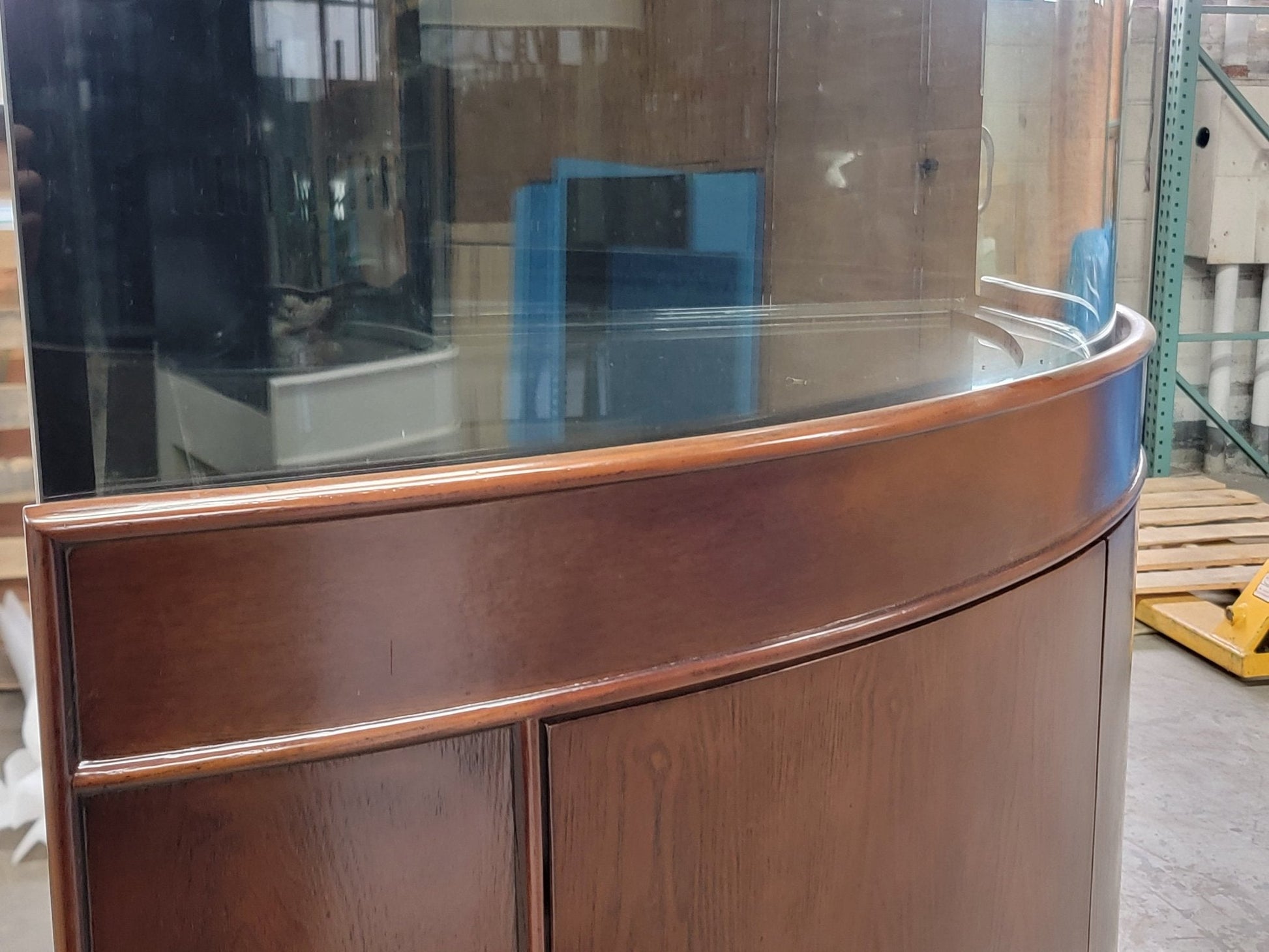 Wooden display case with curved glass top in a warehouse setting