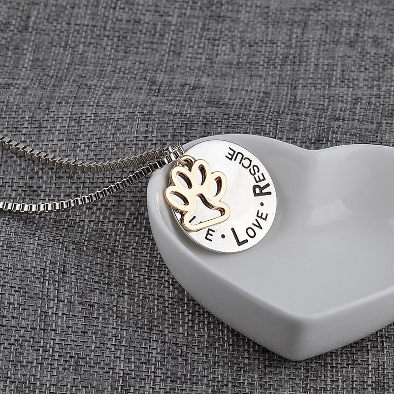 Necklace with a pendant featuring paw prints and text on a textured gray background