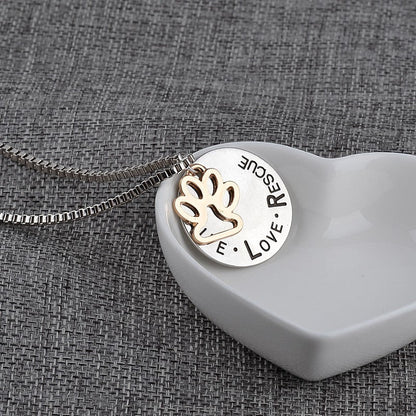 Necklace with a pendant featuring paw prints and text on a textured gray background