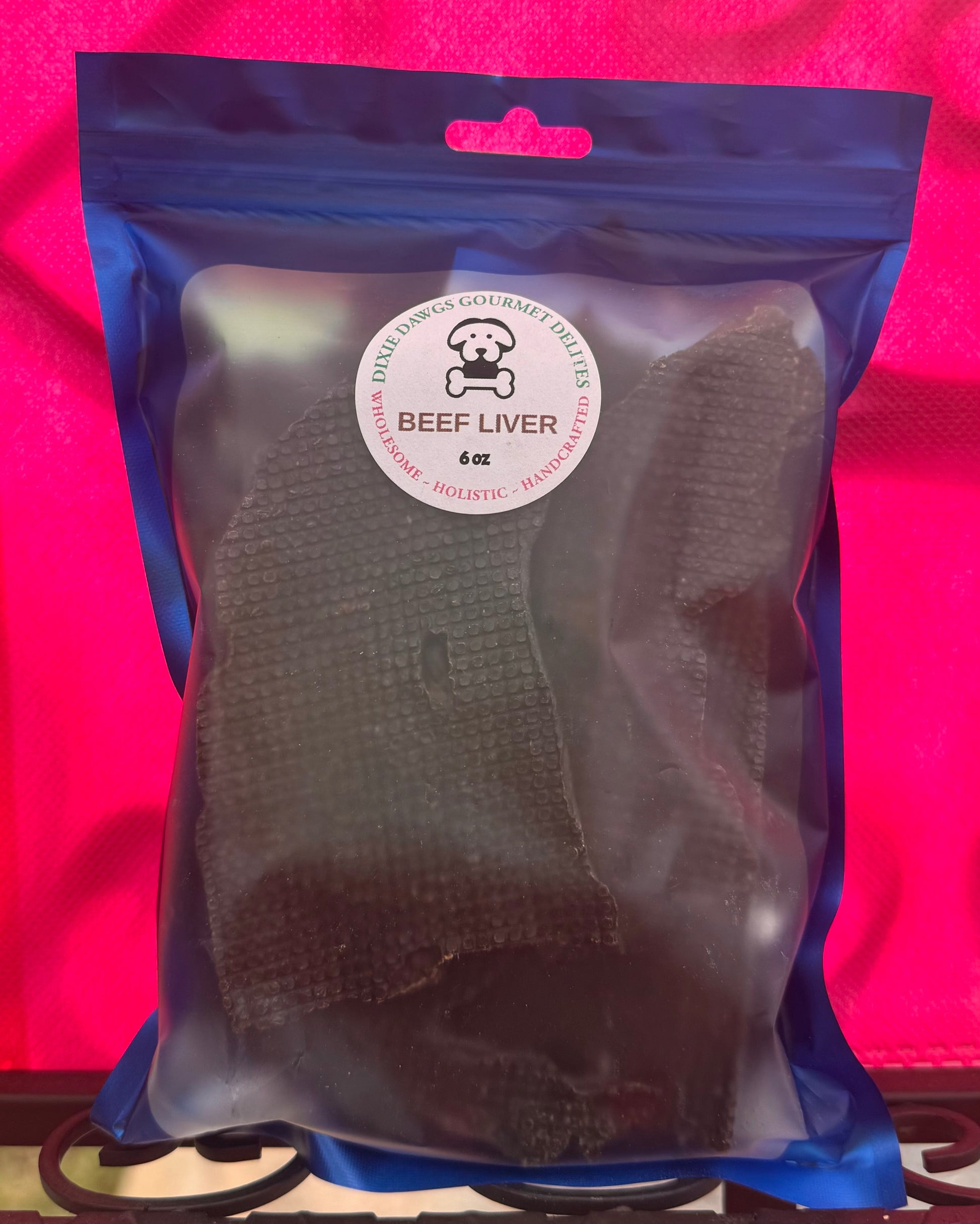 Packaged beef liver treat for pets with a visible brand label on a pink background
