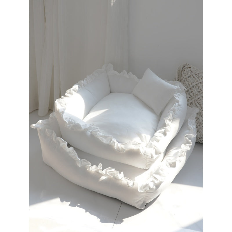 White pet bed with ruffled edges on a light surface