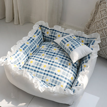 Pet bed with blue plaid pattern and white ruffles on a light background