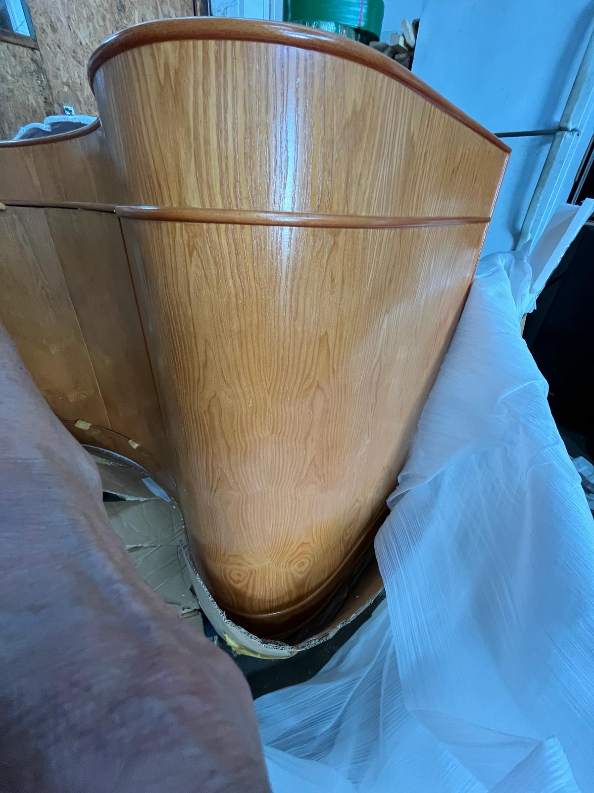 Wooden boat hull with a white plastic bag over it, indoors.