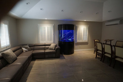 Living room with a large sectional sofa and a cylindrical entertainment unit displaying a blue screen.