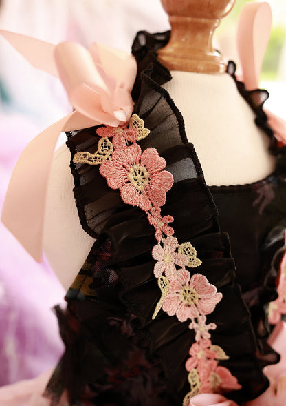 Close-up of black lace with pink floral details held by a hand.