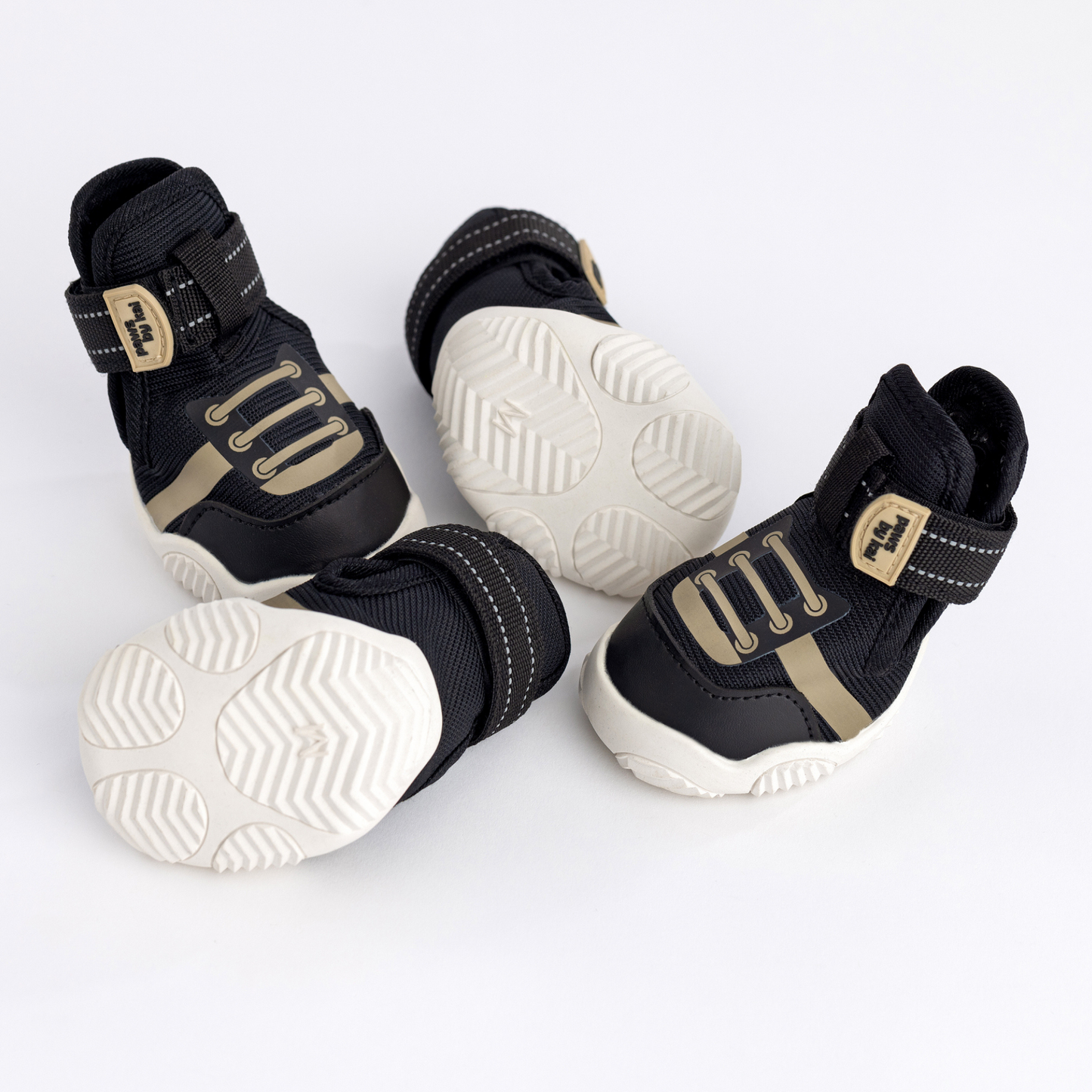 Black and gold pet boots with white soles on a light gray background