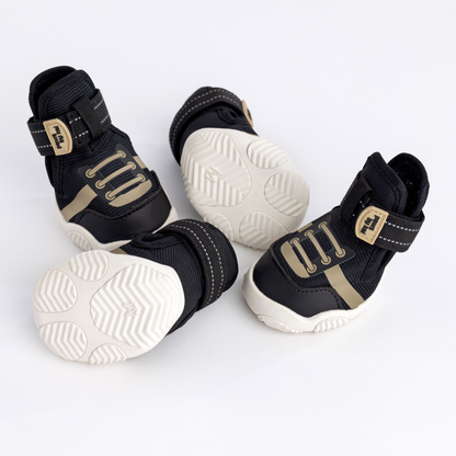 Black and gold pet boots with white soles on a light gray background