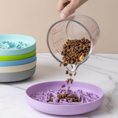 Purple pet bowl with a maze design being filled with dog food using a measuring cup.