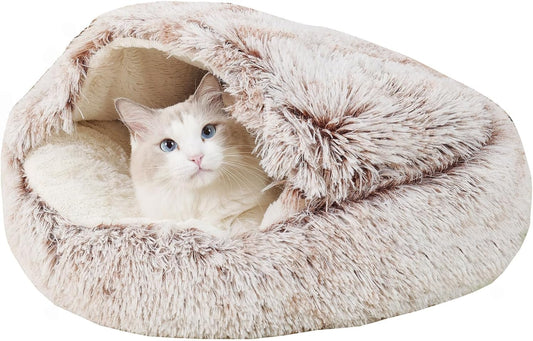 Cat lying comfortably inside a plush, pink, cave-shaped pet bed on a white background.