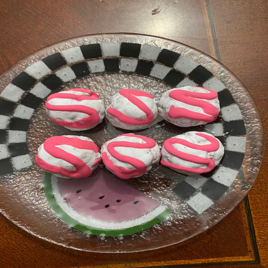 Decorative plate with pink and white cookies and a watermelon slice on a checkered background.