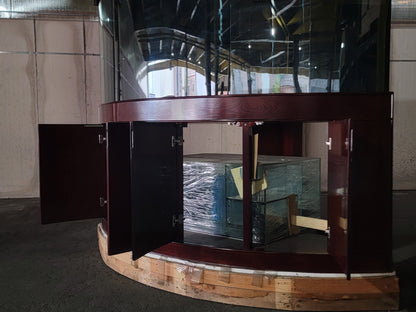Curved wooden reception desk with glass panels in a room with tiled walls.