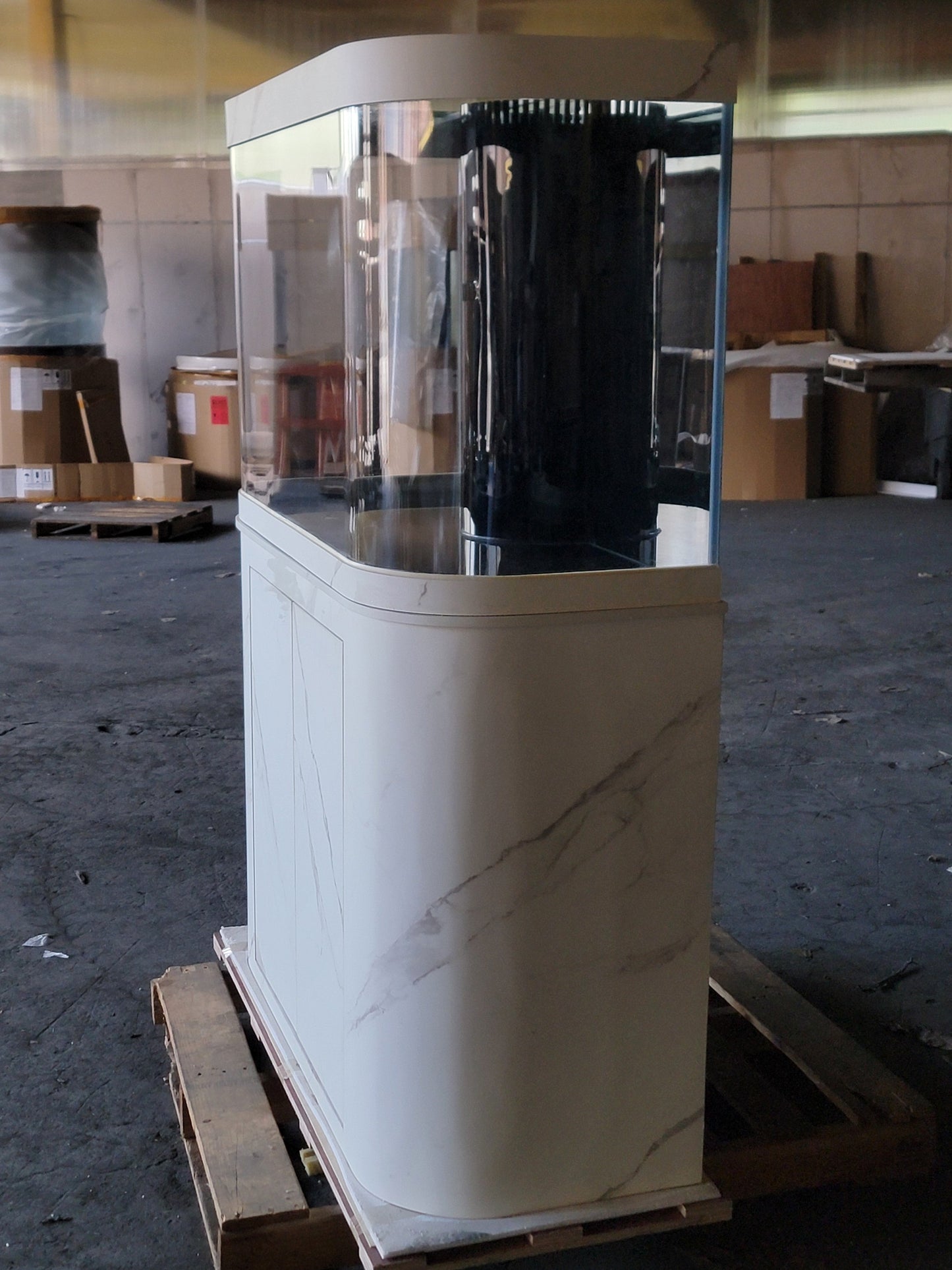White and beige display case on a pallet in an indoor setting with boxes and equipment in the background.
