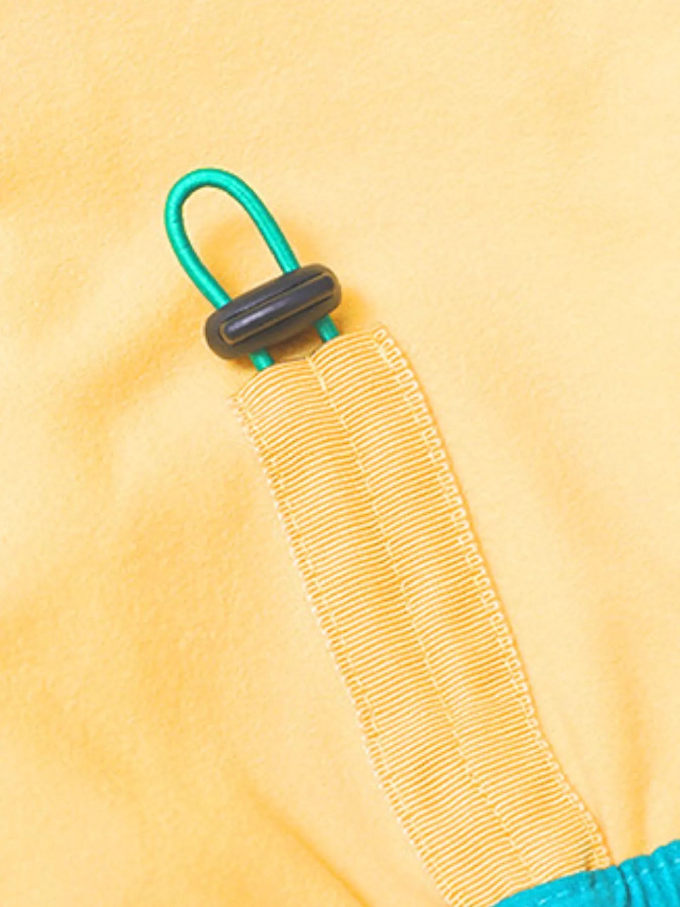 Close-up of a yellow fabric with a green and black buckle on a yellow background