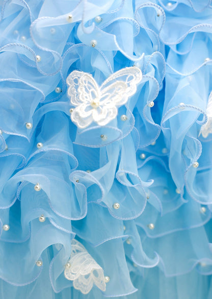 Close-up of light blue fabric with lace butterfly and pearl embellishments
