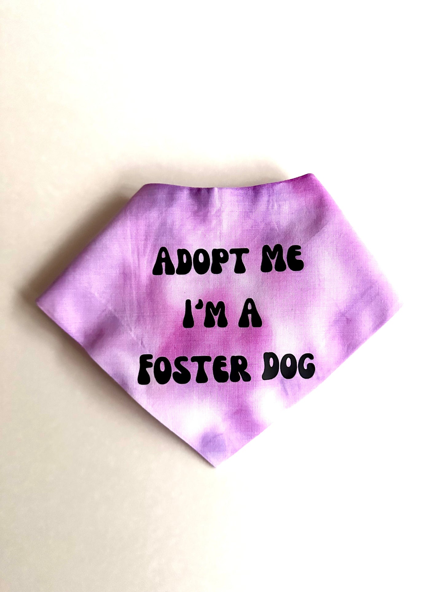Purple tie-dye bandana with 'Adopt Me I'm a Foster Dog' text on a beige background
